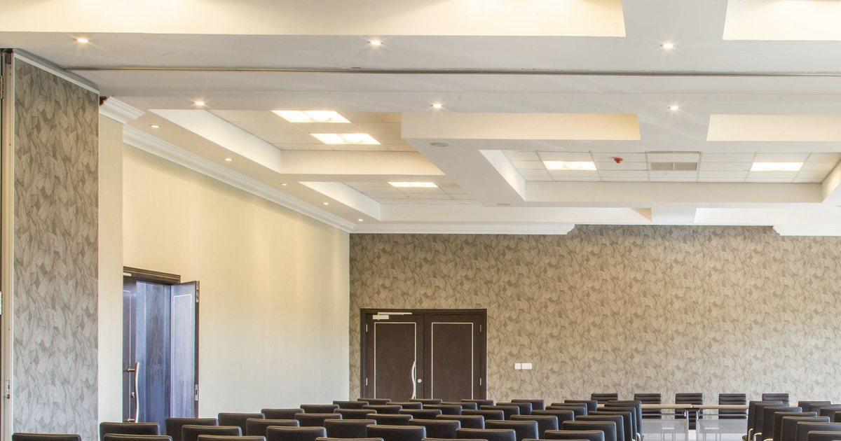Empty function hall with rows of black chairs and wood-panelled doors